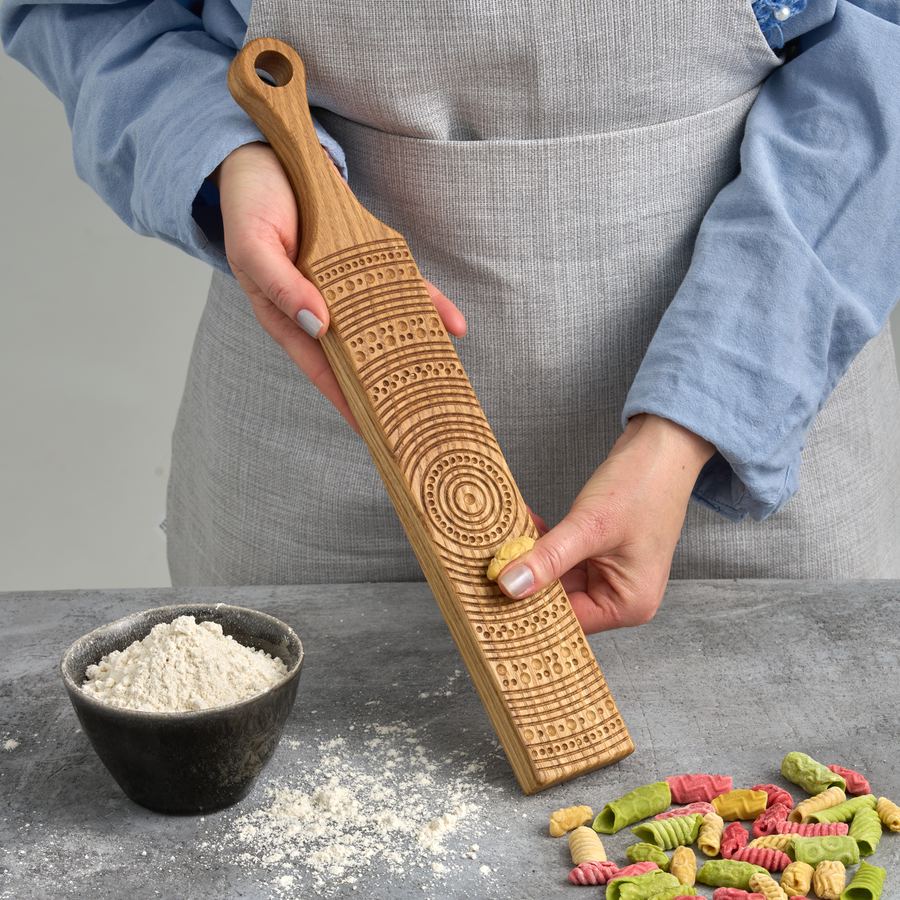 Carved oak gnocchi board held above flour and finished gnocchi
